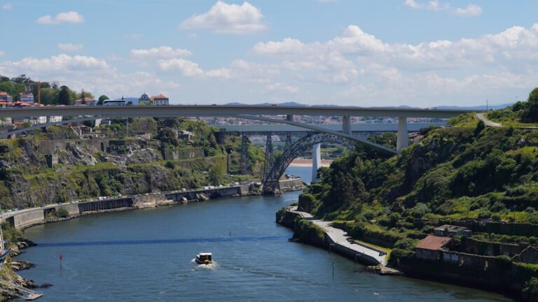 A boat traveling down a river next to a bridge