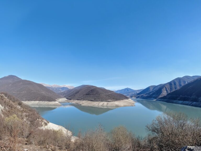 a lake surrounded by mountains under a blue sky