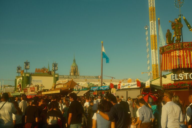 Crowded fairgrounds with rides and tents under blue sky